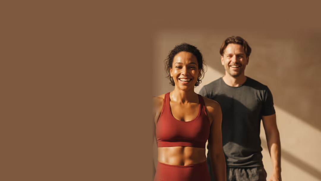 Drei Menschen in Sportkleidung stehen lachend nebeneinander vor einer warmen Wand