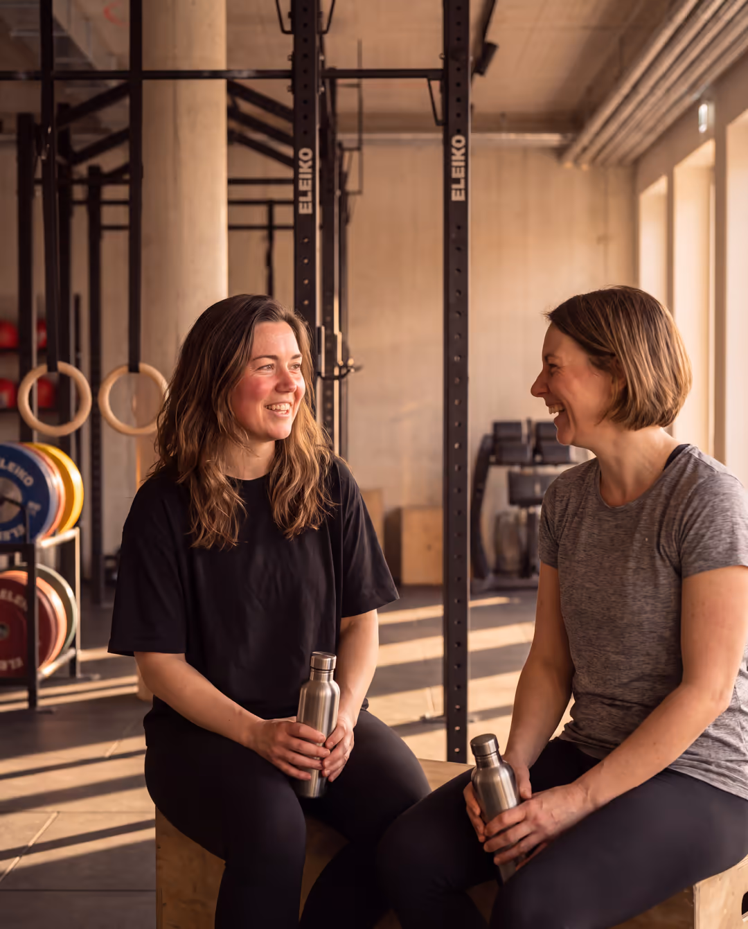 Zwei Frauen sitzen nach dem Coaching auf einer Bank und reden