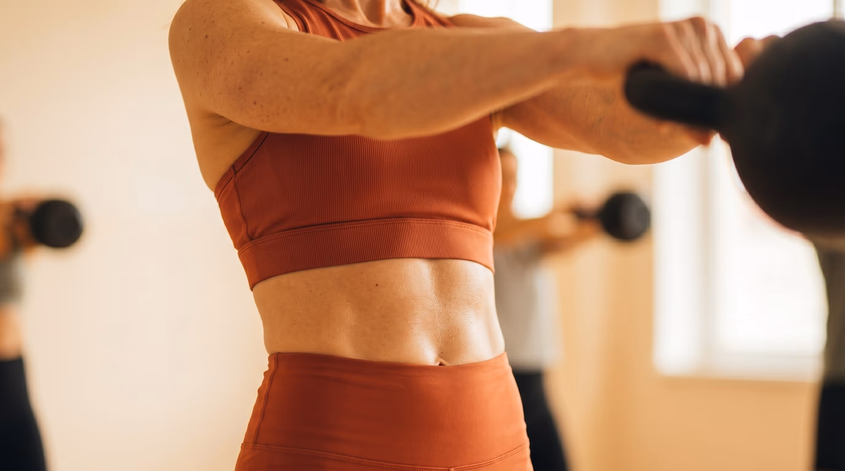 Eine Frau hält eine Kettlebell vor dem Körper.